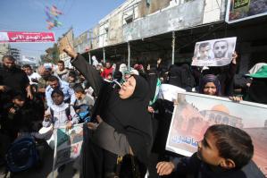 Palestinian woman scatters sweets as she celebrates with others an attack on a Jerusalem synagogue, in Rafah in the southern Gaza Strip
